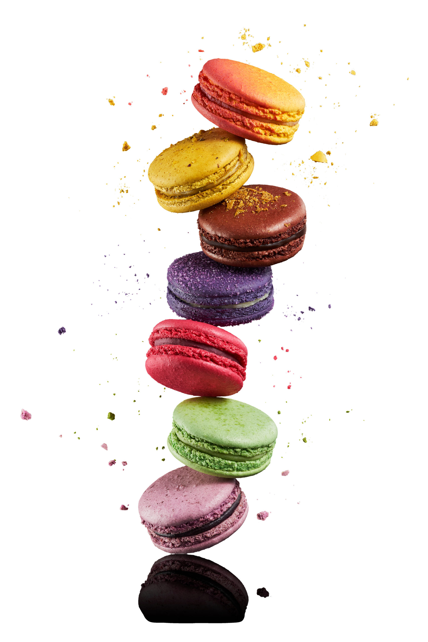 A colorful assortment of gourmet macarons in shades of red, yellow, orange, and purple, achieved with BioconColors high-performance natural colorants for bakery applications.